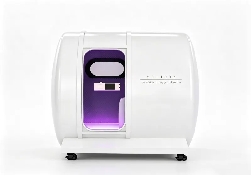 White hard shell hyperbaric chamber with an oval viewing window, interior control panel and purple lighting.